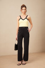 Woman wearing matching knit cardigan vest and trousers set in light color with contrasting trim