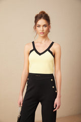 Woman wearing matching knit cardigan vest and trousers set with contrasting trim in light color