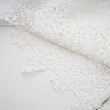 Woman wearing matching white lace trimmed cropped top and trousers set with cutout details