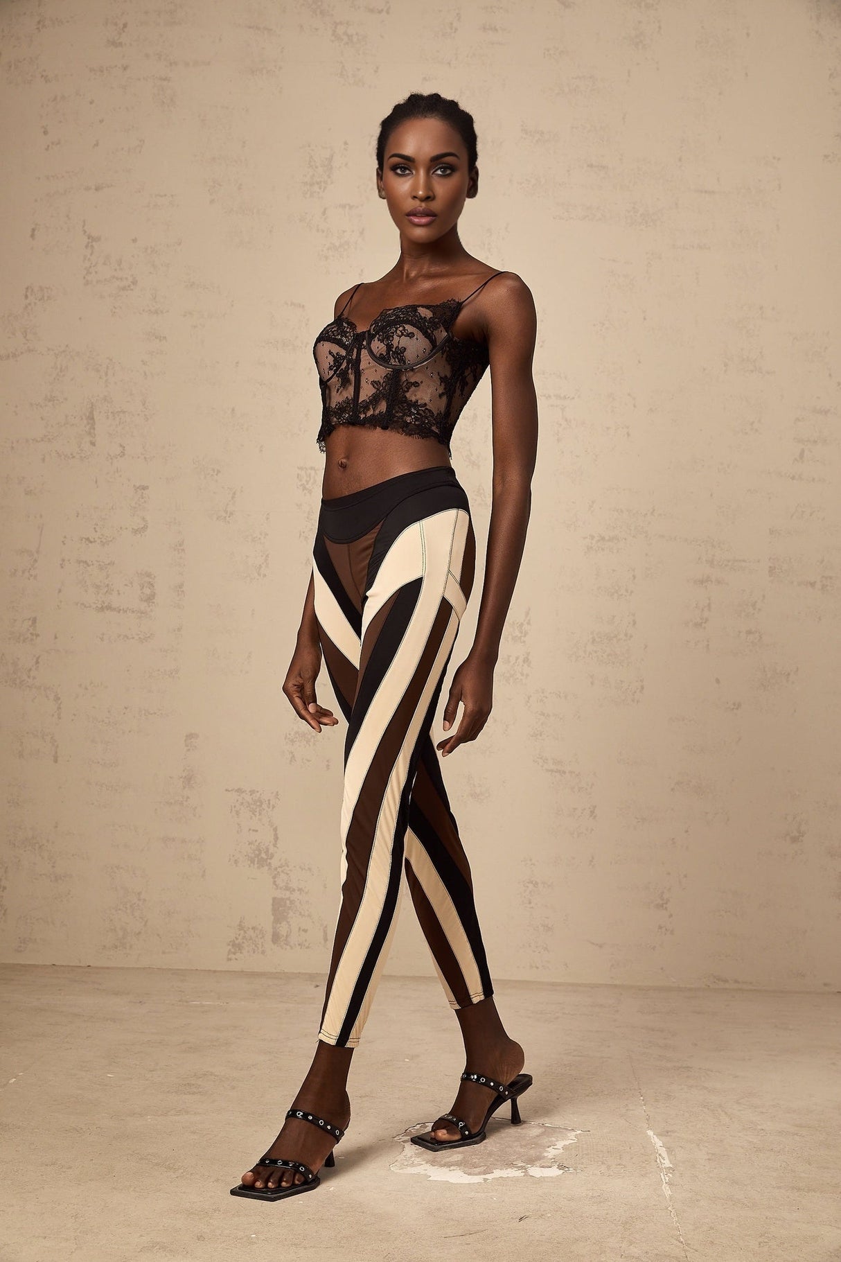 Woman wearing multicolored spiral patterned leggings with color block panels in vibrant hues standing against plain background