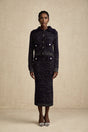 Woman wearing navy blue crochet knit jacket and matching skirt set standing against plain background