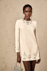 Woman wearing neutral color long sleeve mini dress with crystal embellishments