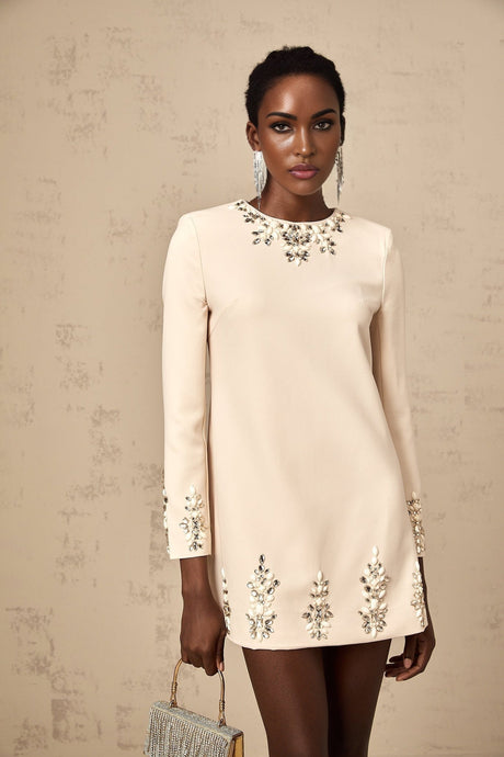 Woman wearing neutral color long sleeve mini dress with crystal embellishments