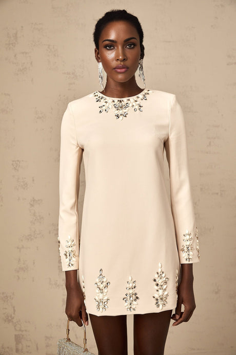 Woman wearing neutral colored long sleeve mini dress adorned with crystal embellishments