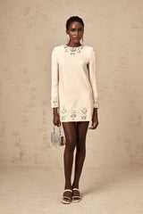 Woman wearing neutral colored long sleeve mini dress adorned with crystal embellishments