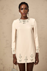 Woman wearing neutral colored long sleeve mini dress adorned with crystal embellishments