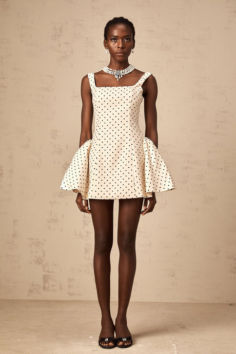 Woman wearing neutral colored mini dress with polka dot pattern and puff sleeves