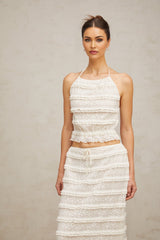 Woman wearing off white floral lace matching set with ruffled top and skirt called Heloise