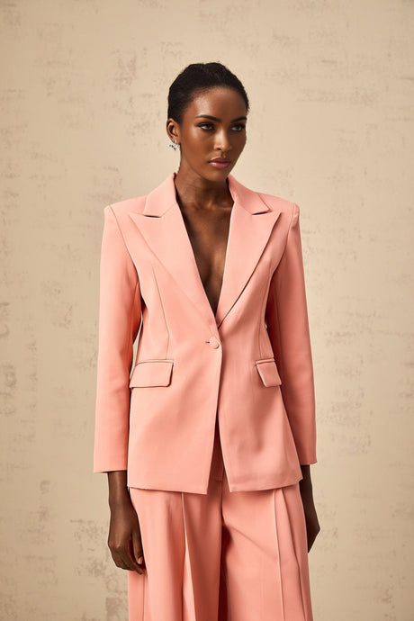 Woman wearing pink blazer and trousers set with embroidery details and cutout design