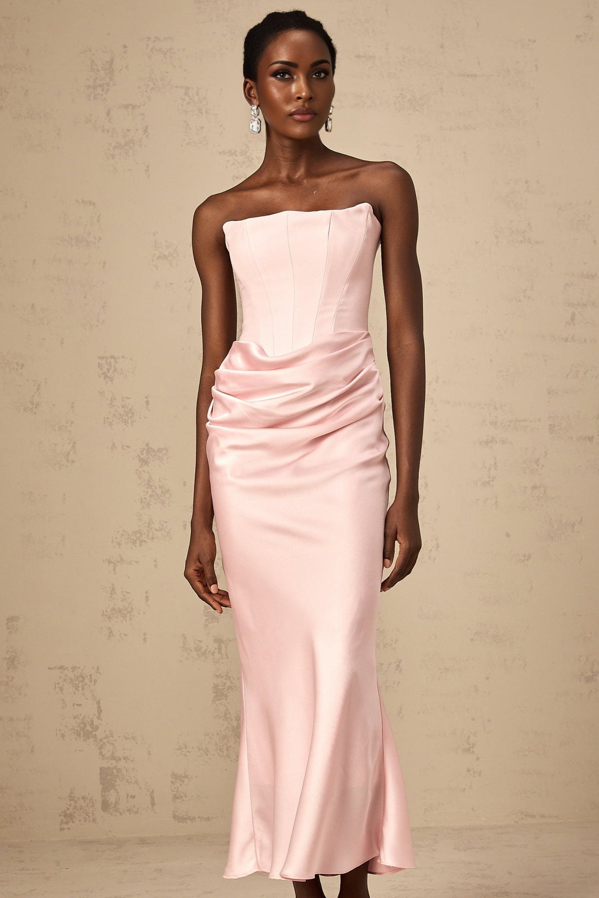 Woman wearing pink offshoulder maxi dress with flowing skirt standing in sunlit garden