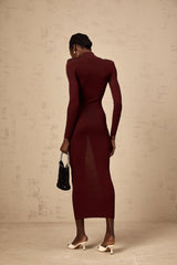 Woman wearing red knitted midi dress with semi sheer fabric standing against plain background