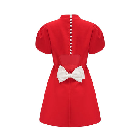 Woman wearing red mini dress with petal sleeves cut out details and bow accent