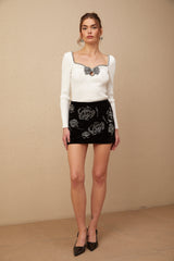 Woman wearing shiny black velvet mini skirt adorned with sparkling sequins
