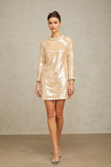 Woman wearing short beige dress with faux pearl and sequin embellishments