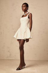 Woman wearing short beige dress with white polka dots and puff sleeves