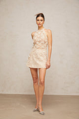 Woman wearing short beige lace dress with floral appliques and sheer sleeves
