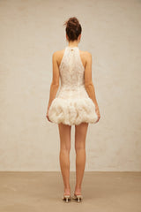 Woman wearing short beige mini dress with puff sleeves and textured fabric
