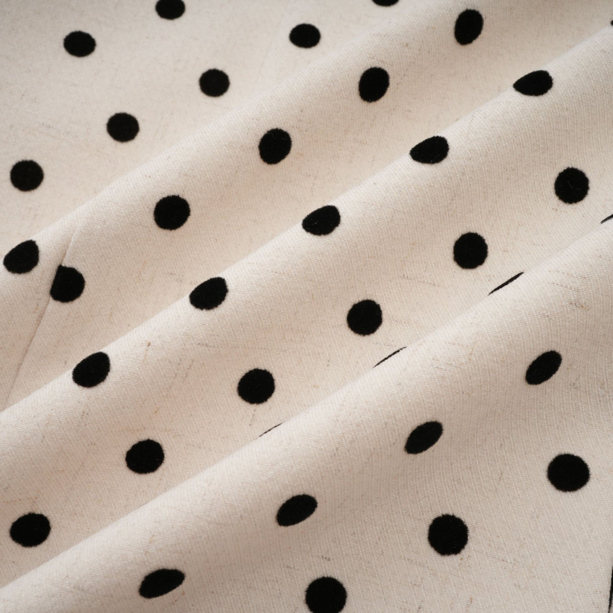 Woman wearing short beige mini dress with white polka dots and puff sleeves