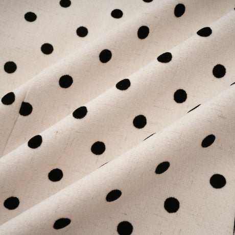 Woman wearing short beige mini dress with white polka dots and puff sleeves