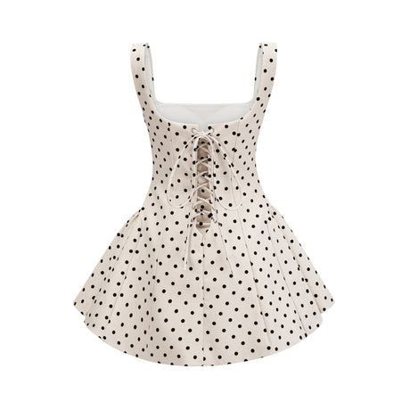 Woman wearing short beige polka dot dress with puffed sleeves and gathered waist