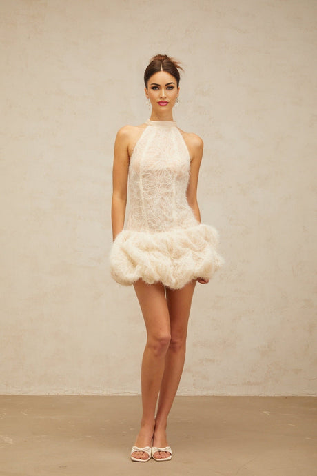 Woman wearing short beige textured mini dress with puff sleeves and gathered fabric detail
