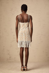 Woman wearing short black dress with sparkly embellishments and fringe details at hem