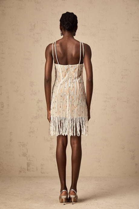 Woman wearing short black dress with sparkly embellishments and fringe details at hem