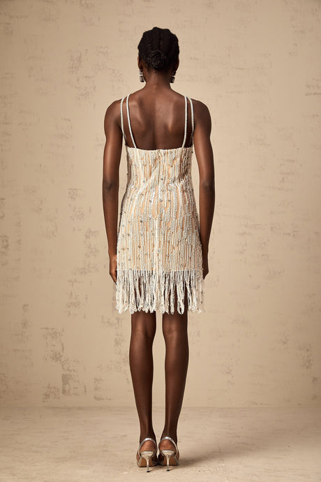 Woman wearing short black dress with sparkly embellishments and fringe details at hem