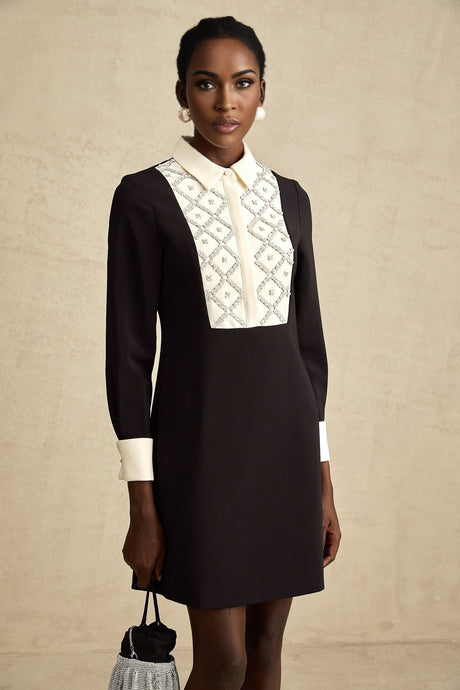 Woman wearing short black dress with white collar and cuffs embellished with crystals