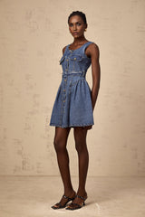Woman wearing short blue denim dress with belt cinched at waist