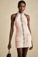 Woman wearing short halterneck dress with crystal embellishments in light color shimmering fabric flared skirt and open back