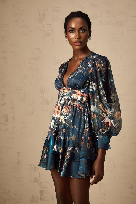 Woman wearing short light blue dress with graphic print pattern and embellishments