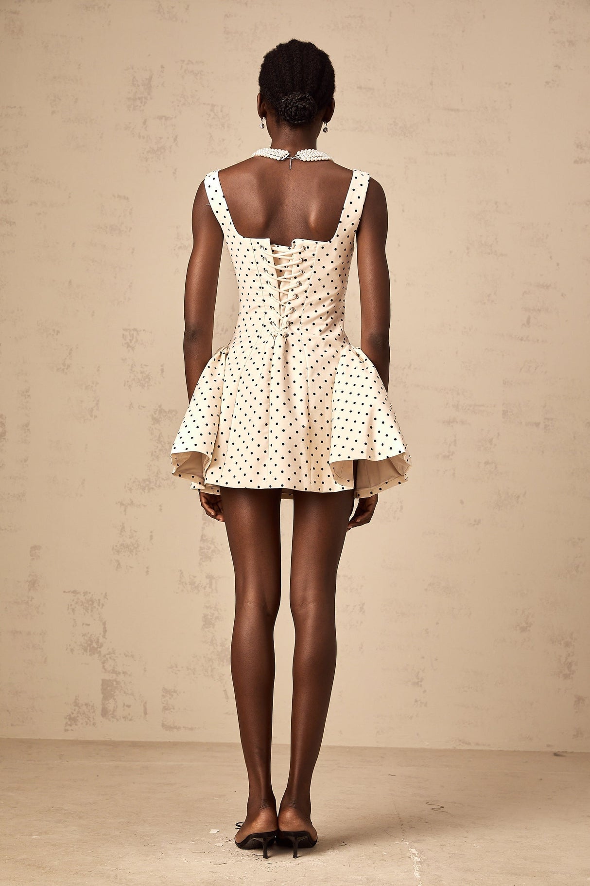Woman wearing short polka dot dress with puff sleeves in neutral tones