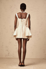 Woman wearing short polka dot dress with puff sleeves in neutral tones