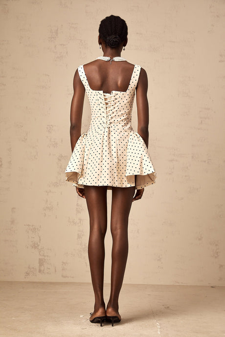 Woman wearing short polka dot dress with puff sleeves in neutral tones
