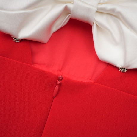 Woman wearing short red dress with petal sleeves cut out detail and bow accent