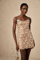 Woman wearing short sparkling silver dress with sequin embellishments and long sleeves