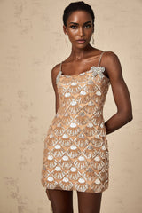 Woman wearing short sparkly gold dress with long sleeves and high neckline