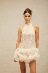 Woman wearing short textured mini dress in neutral color with puffed sleeves and relaxed fit