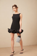 Woman wearing short white ruffled dress with open back design standing in relaxed pose