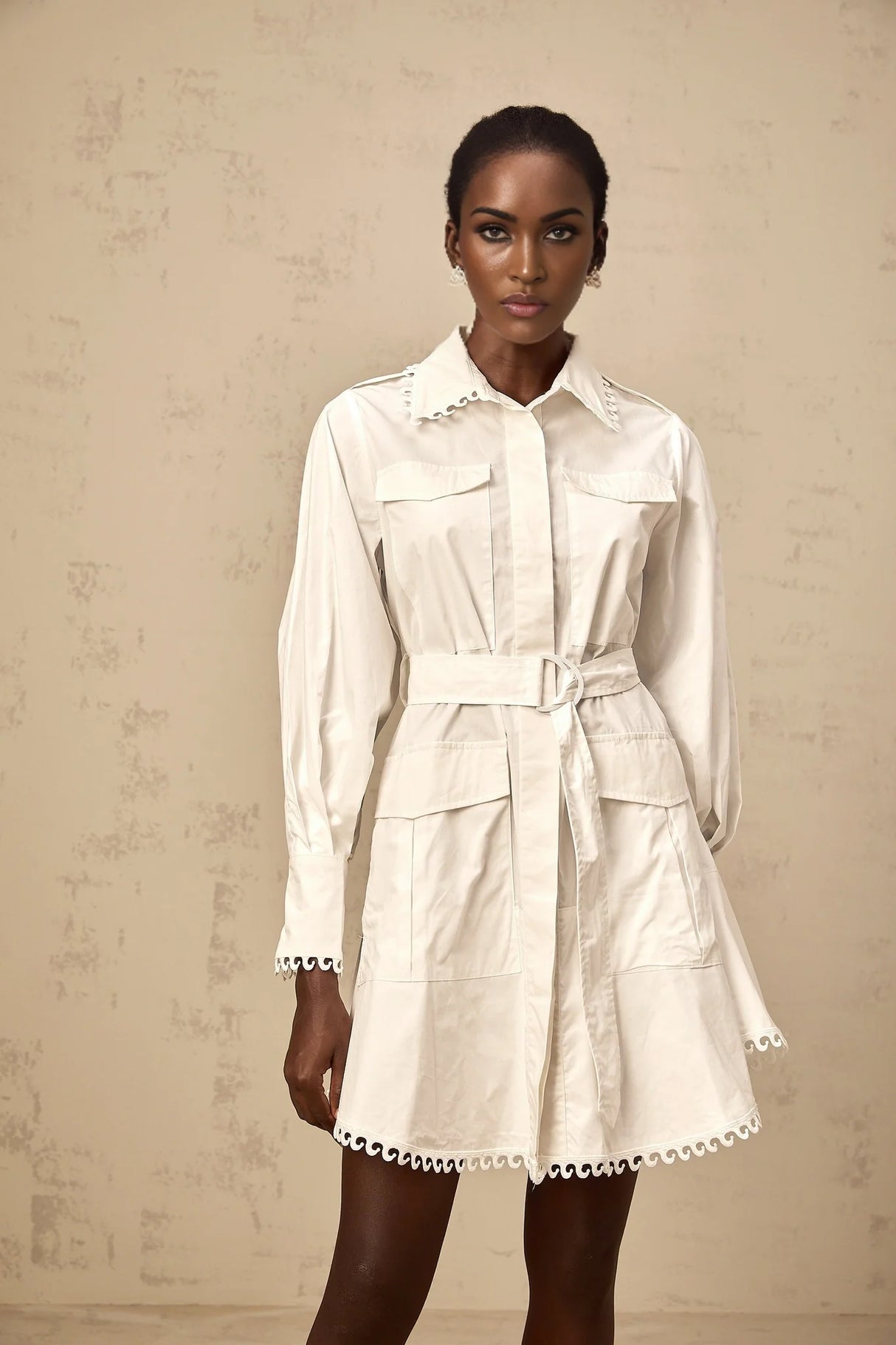 Woman wearing short white shirt dress with belt at waist and buttonup front
