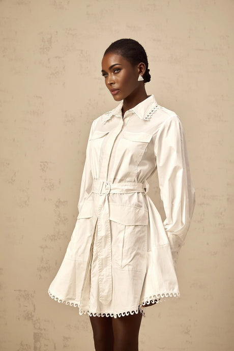 Woman wearing short white shirt dress with belt cinched at waist