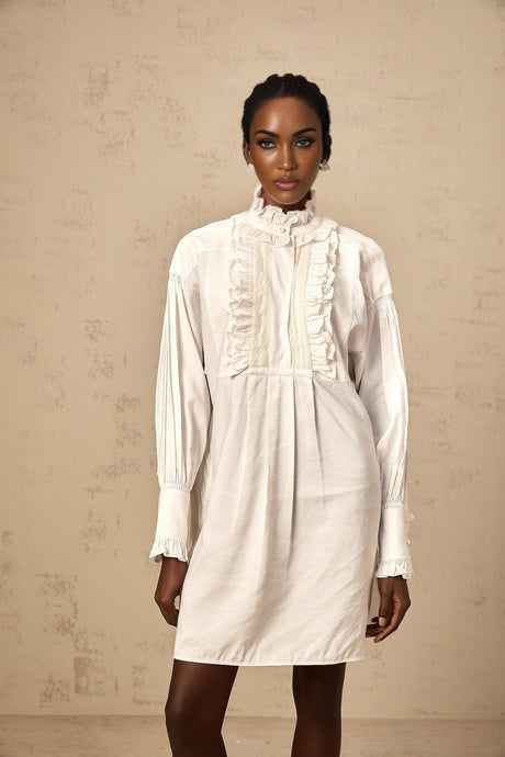 Woman wearing short white shirt dress with lace trim and ruffled details