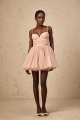 Woman wearing short white sleeveless dress with pleated tulle skirt