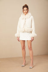 Woman wearing short white suede coat with fur trim and padded design