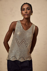 Woman wearing sleeveless gold vest top with sequin embellishments and crochet pattern