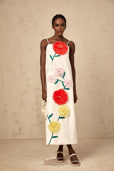 Woman wearing sleeveless white midi dress with 3d petal details on bodice