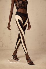 Woman wearing spiral color block panelled leggings in vibrant colors with a swirling pattern on the legs