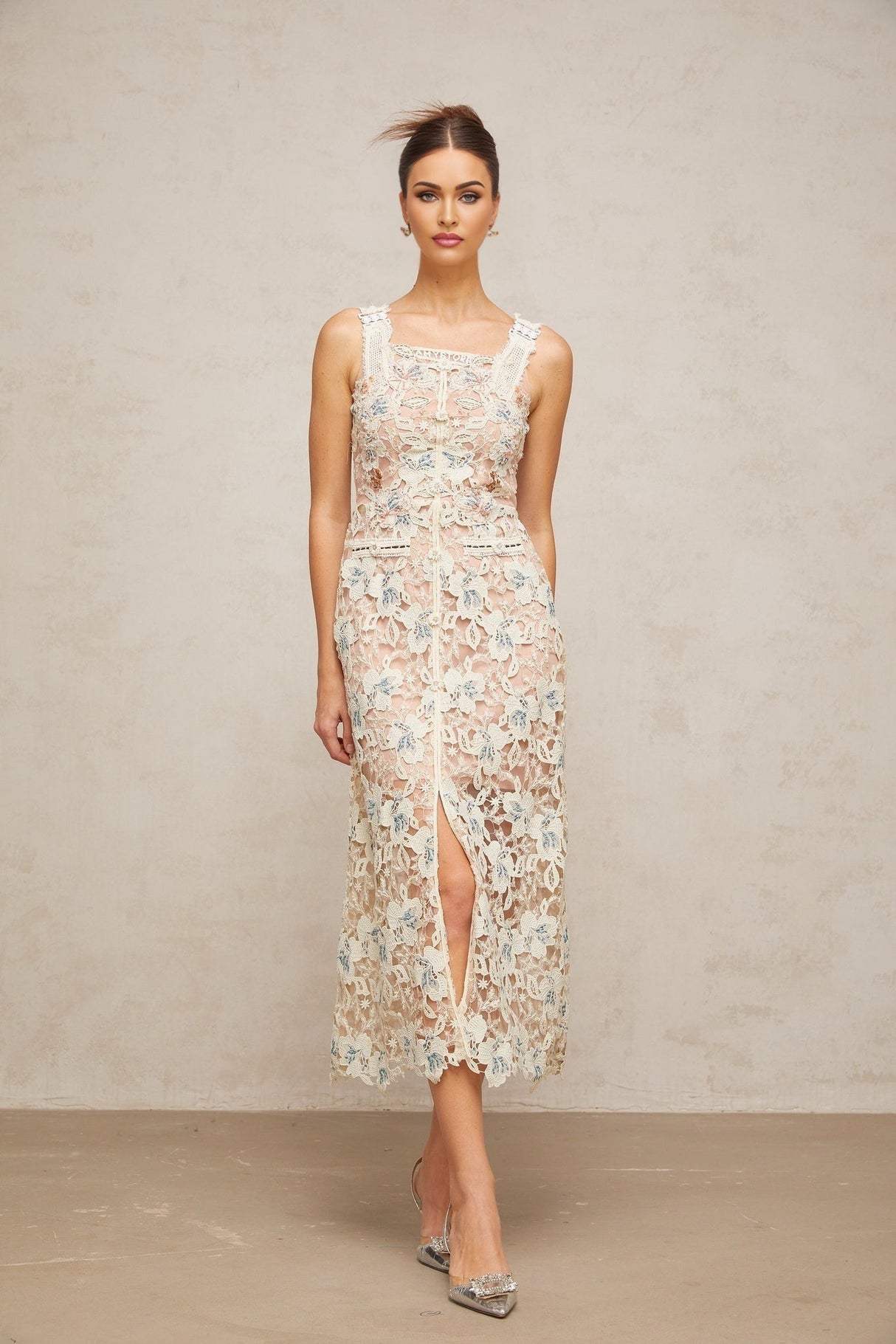 Woman wearing white Aline midi dress with floral lace pattern standing in neutral background