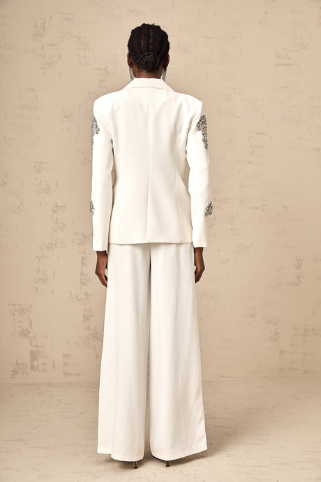 Woman wearing white blazer and trousers set embellished with crystal details